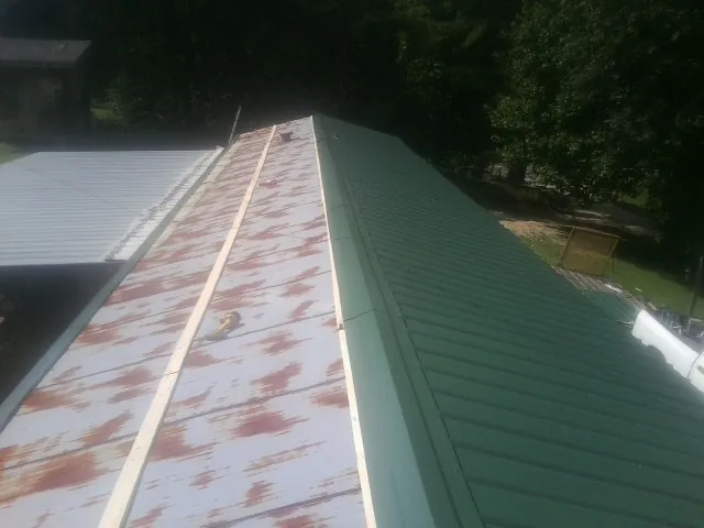 Old rusted panels beside newly installed green metal roofing — Wind Damage Roof Repair by Roofing Brothers in Irmo