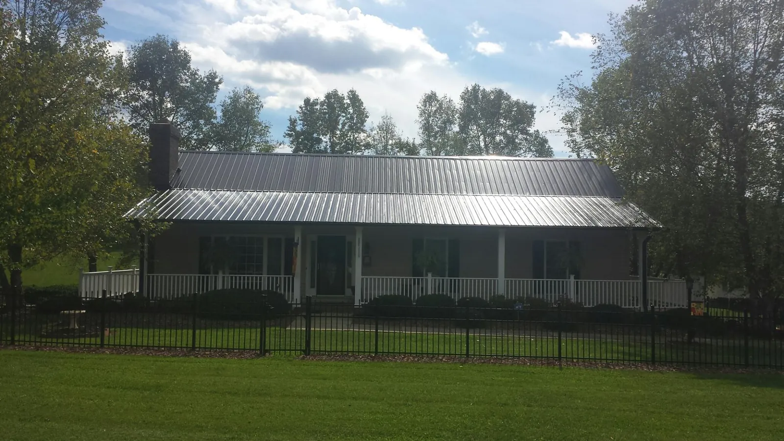 Gray metal roof on a brick ranch with a full width front porch — Gutter Guard Installation work by our crew in Irmo