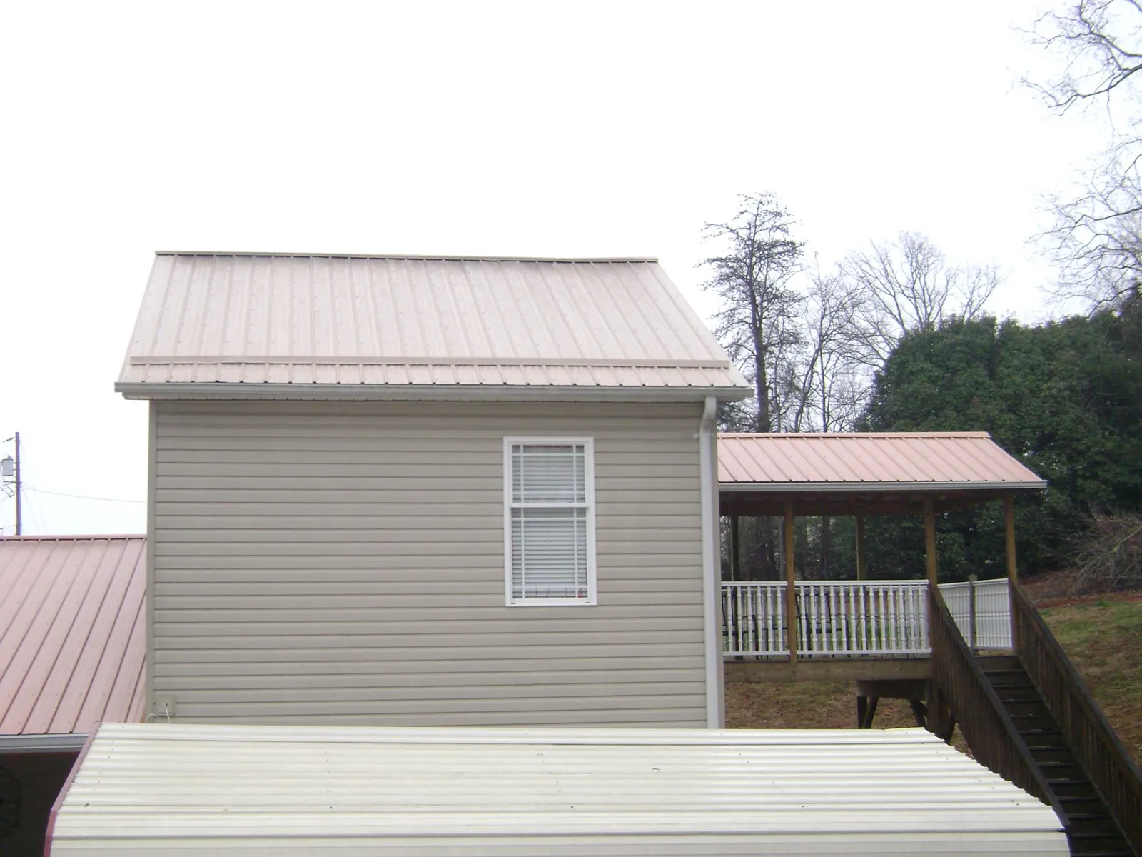Tan metal roofs on a two story addition and attached porch, from a Roof Replacement job in Irmo