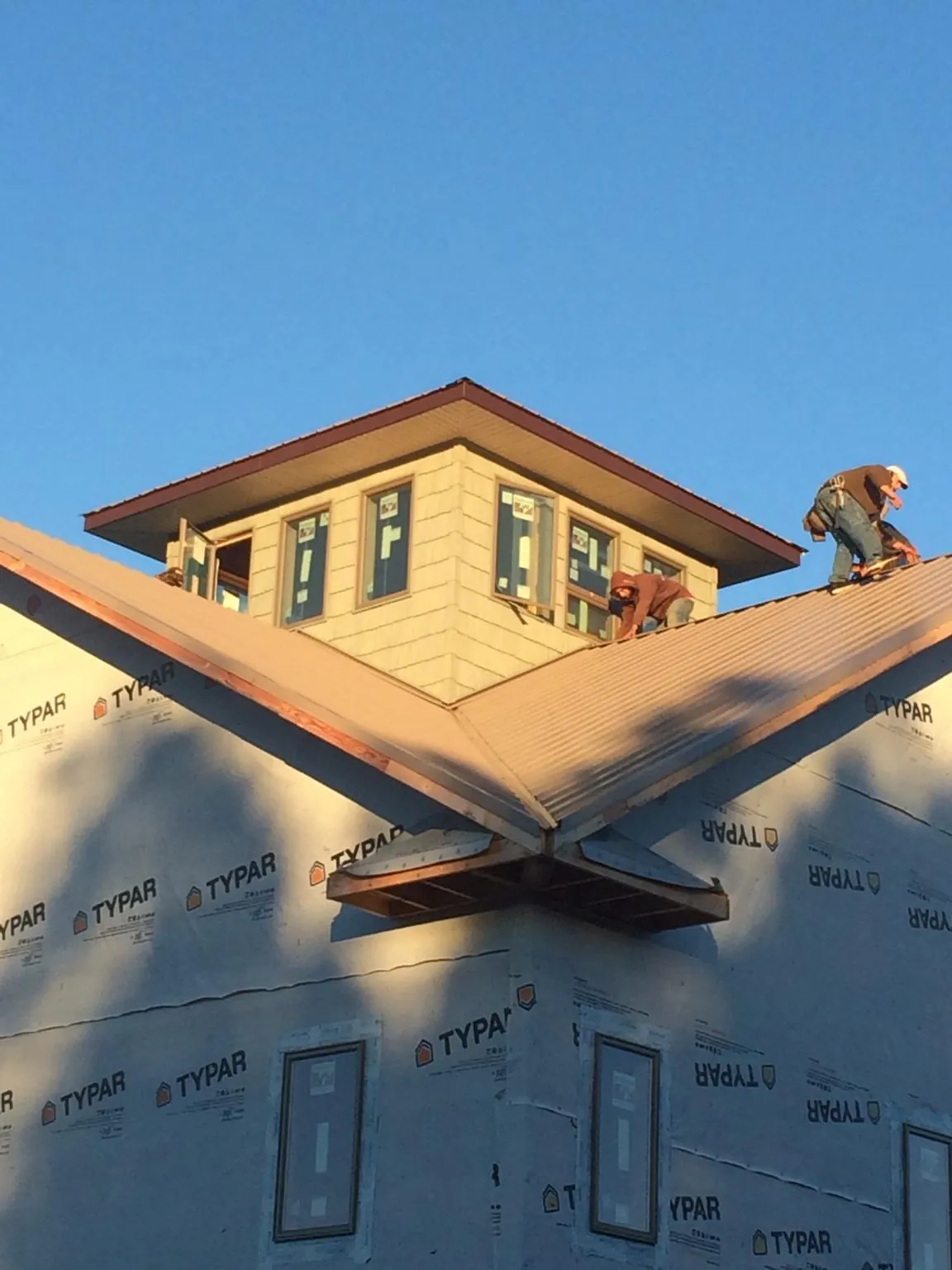 Roofers working around a rooftop cupola on a new metal roof at sunset — Roof Waterproofing in Irmo by Roofing Brothers